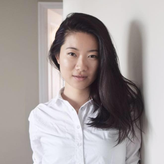 Woman in a white blouse leaning against a white wall