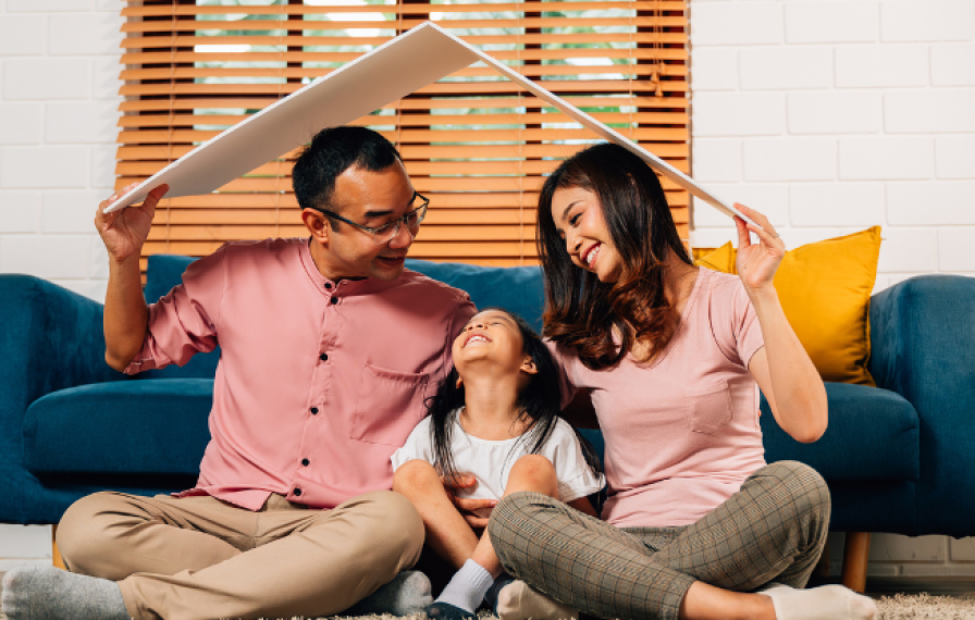 A family in front of a sofa playing with a cardboard roof over their heads