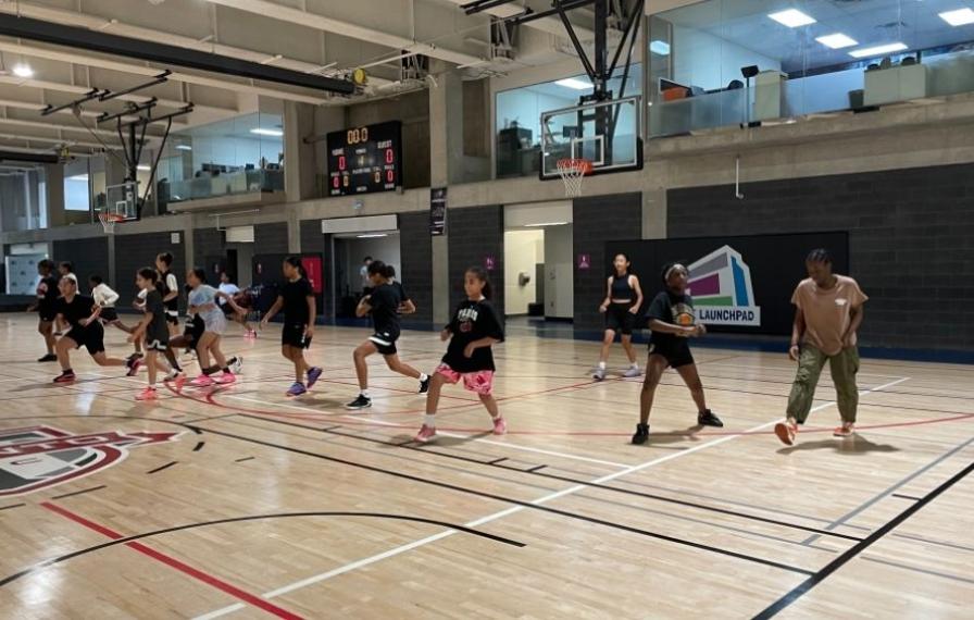 A group of young girls exercising on a basketball court. 