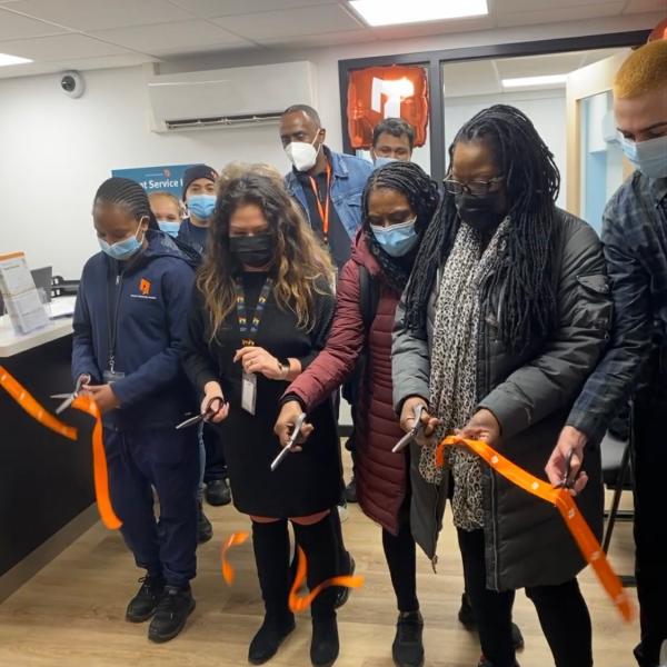 People in winter clothes and face masks cutting an orange ribbon at the 245 Dunn Ave Tenant Service Hub