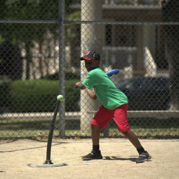 A young boy practicing baseball batting outdoors. 