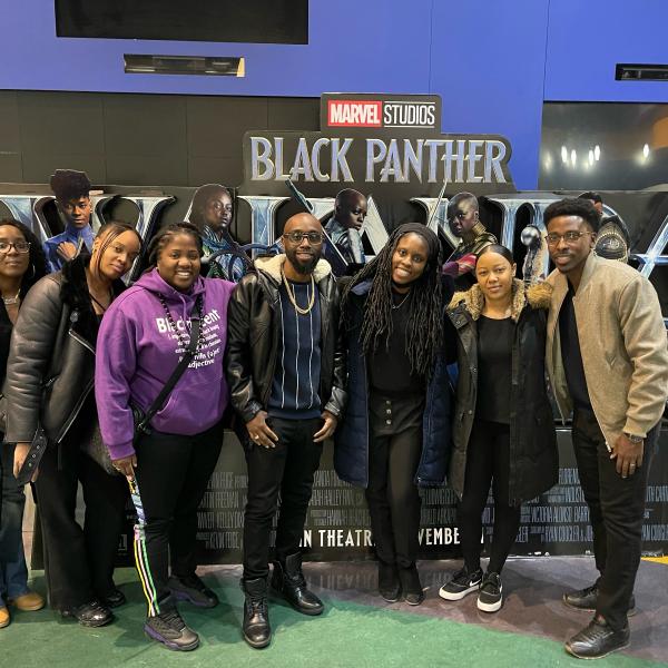 Staff in front of a Black Panther movie poster