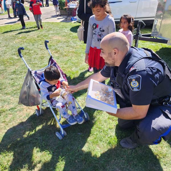 A CSU officer kneels to talk to a child in a stroller