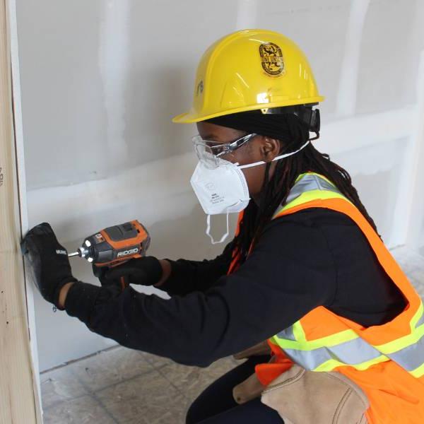 Person using a drill to install drywall.