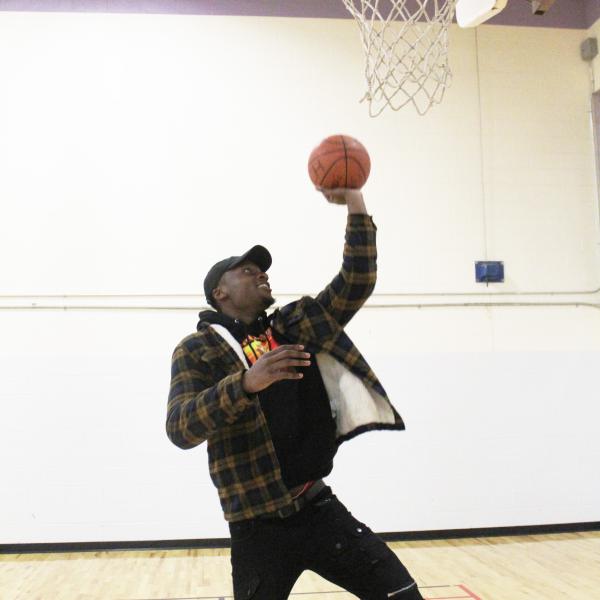 Man making a layup indoors with one hand