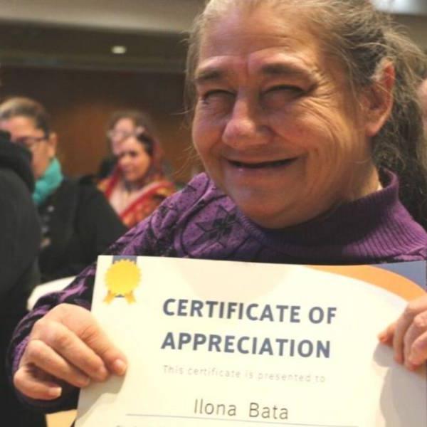 A person holding up a certificate that says Certificate of Appreciation presented to Ilona Bata.