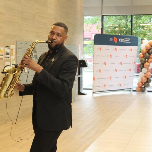 A male saxophonists performing at an event. 
