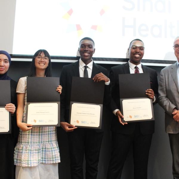 Four youth holding their certificates while standing with a IIODS donor. 