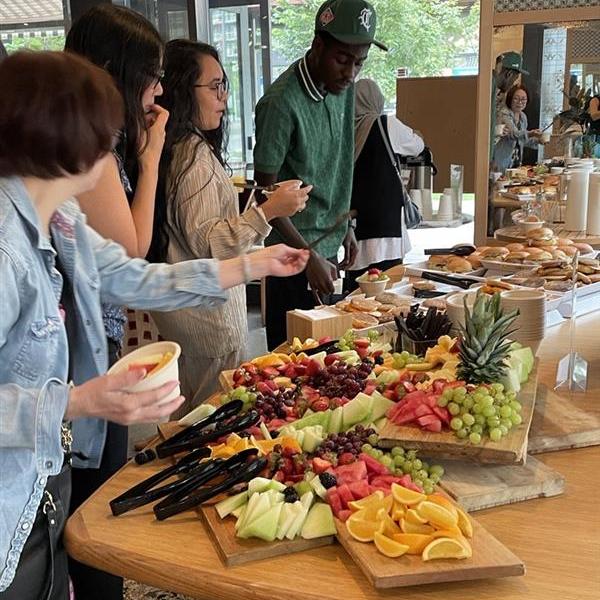 A group of people taking food from a table as they stand in line. 