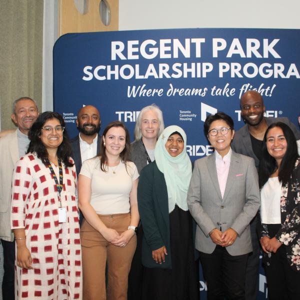 A group of people posing for a photo behind the Regent Park Scholarship program backdrop.