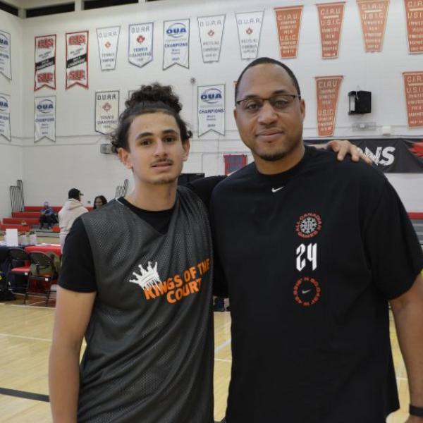 Two people standing in a gym posing for a camera.