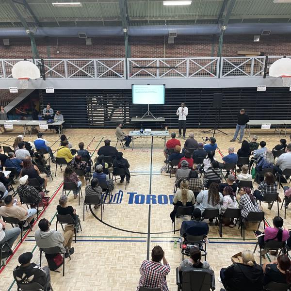 Overhead shot of crowd seated in a gym at the 300 Dufferin project meeting