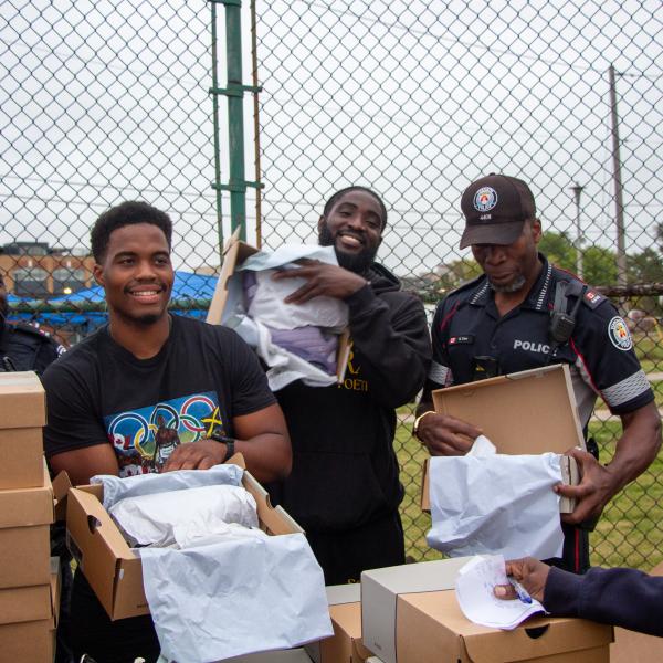 TCHC People’s Choice Award Winner for Emerging Leader, Trevaun Douglas, works with members of Toronto Police Service to distribute running shoes to residents in his community. 