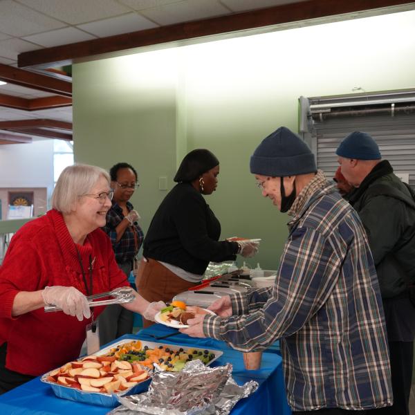 TCHC staff serving pancakes, bacon and fruits to the tenants.