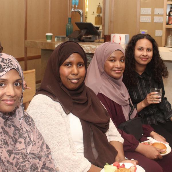 Four women sitting in chairs and smiling for the camera.