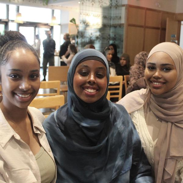 Three ladies sitting and smiling for the camera at an event. 