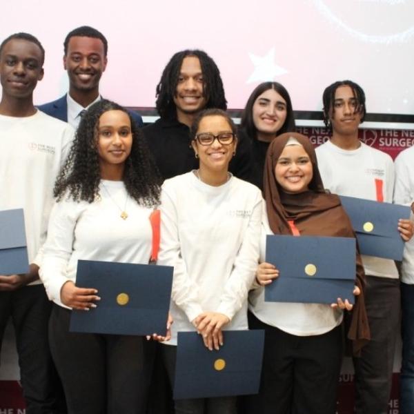 A group of people standing in front of a screen smiling for a camera.