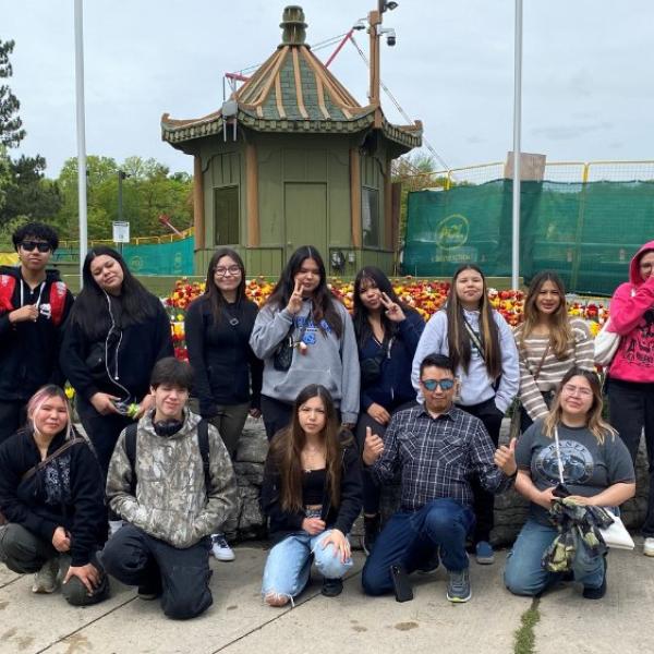 A group of people smiling for a photo in front of the entrance of the Zoo. 