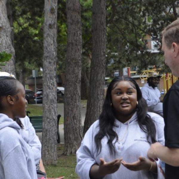 A man speaking to a group of youth.