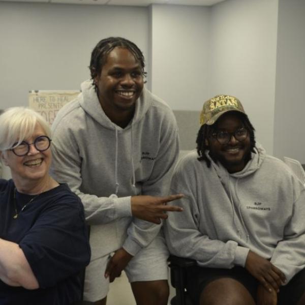 Three individuals sitting in a room posing for a photo