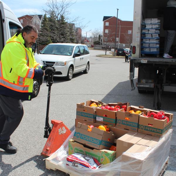 A volunteer uses a forklift to move boxes of fresh produce