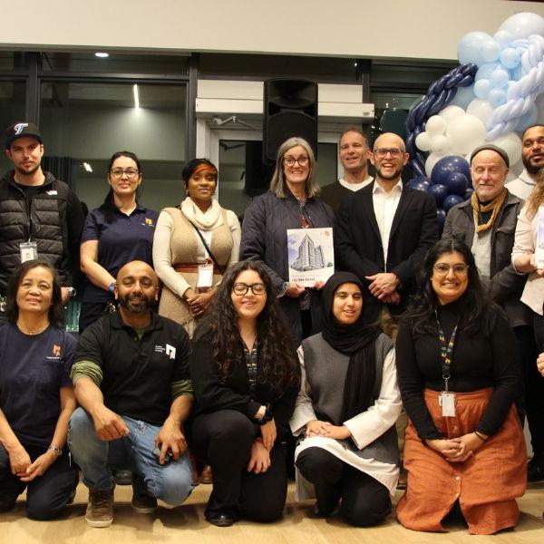 A group photo of TCHC staff holding "welcome home" guide books and smiling.