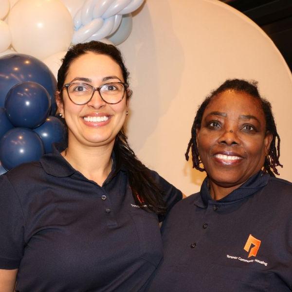 Two TCHC staff members smiling in front of balloons.