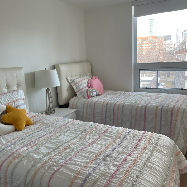 A bedroom with two beds, one with a pink pillow and the other with a yellow pillow.