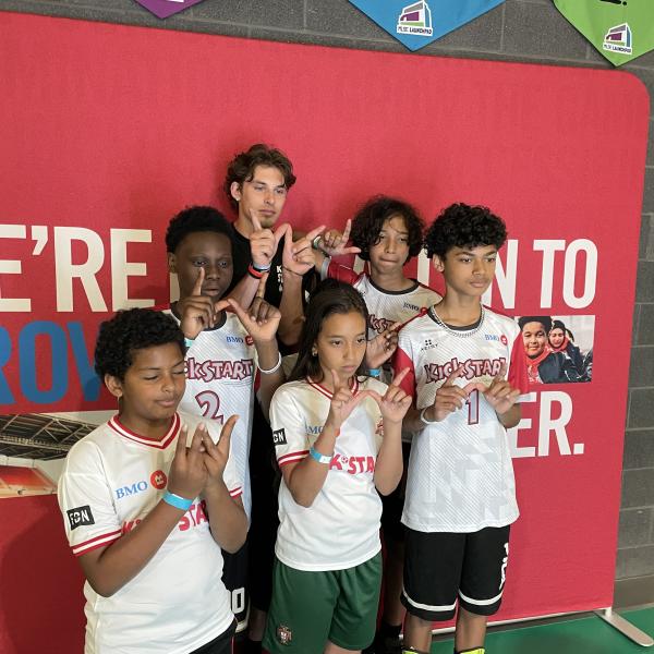 A group of children in athletic outfits posing with a TCHC staff member.