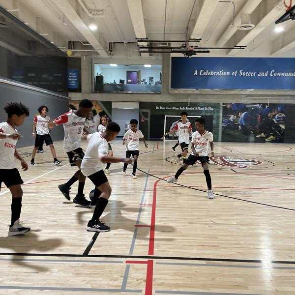 A group of children playing soccer in a gymnasium.
