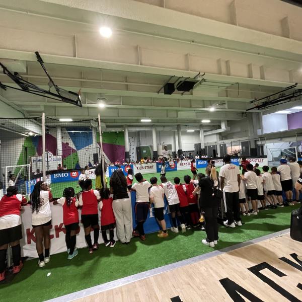 A group of adults and children watching an indoor soccer game.
