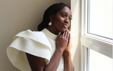 A photo of Precious - a woman wearing a white shirt looking out of a window.