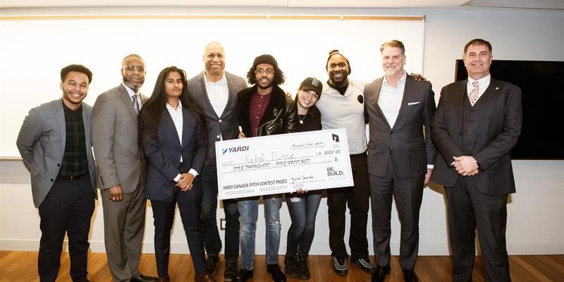 Group photo of tenants and staff holding a cheque