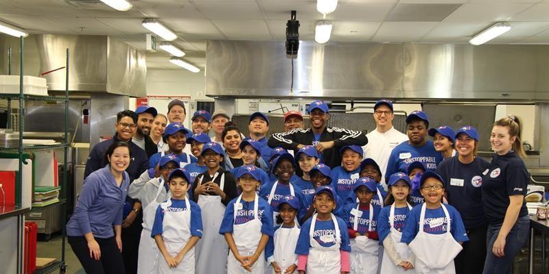 Group tenant youth and staff in a kitchen wearing aprons