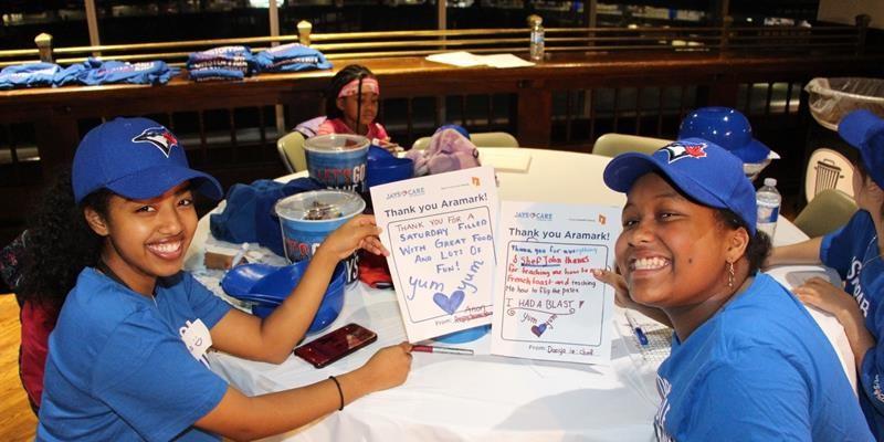 Tenant youth posing at a table and holding up letters