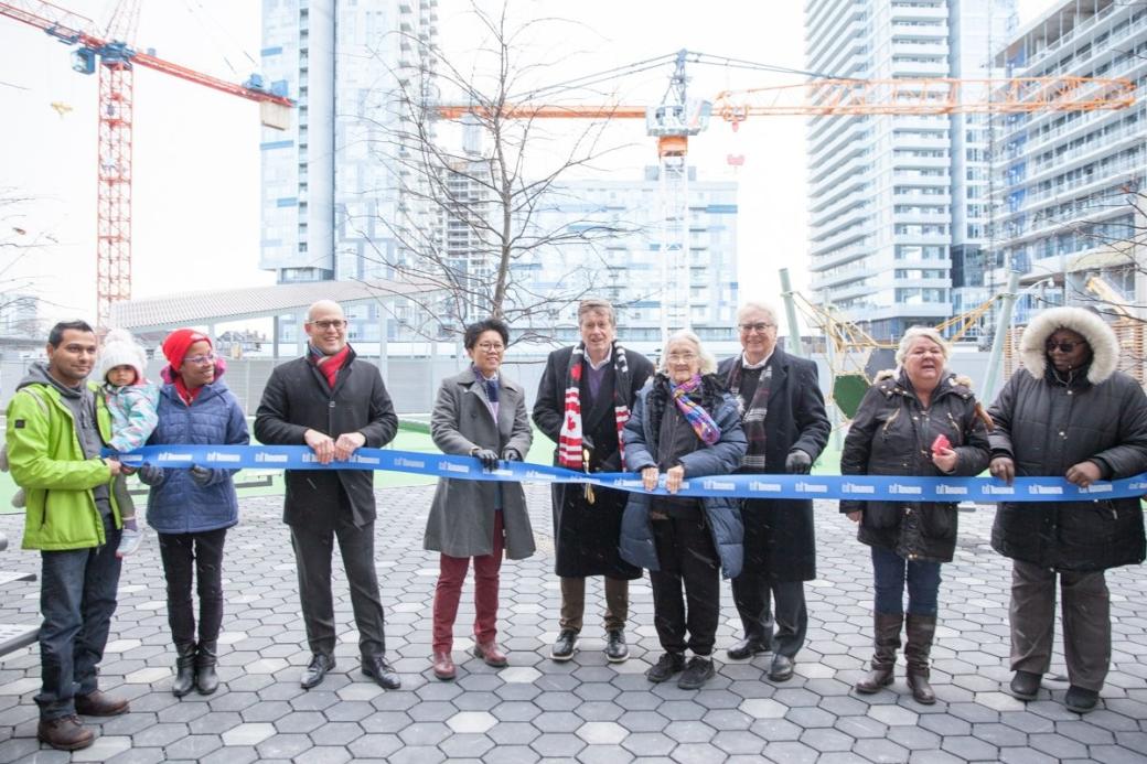 Group photo of staff outdoors preparing to cut a ribbon