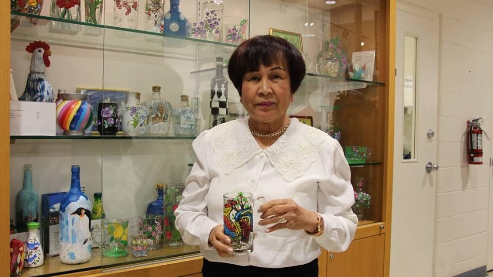 Rosalinda Gindap poses with her masterpiece of a rooster painted on a glass mug.