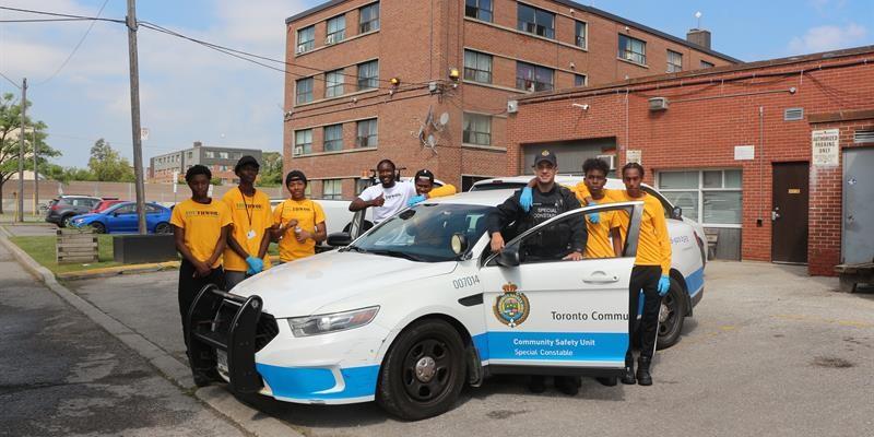 Group photo of tenants and staff around a car