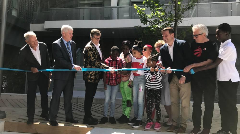 Mayor John Tory (middle) joins (left to right) Context CEO Howard Cohen, Toronto Community Housing CEO Kevin Marshman, tenant Nicola Rose and family, MPP Robin Martin, MP Marco Mendicino, Councillor Mike Colle and event co-emcee Isaiah Afrira to officially open the 20 Zachary Court building.