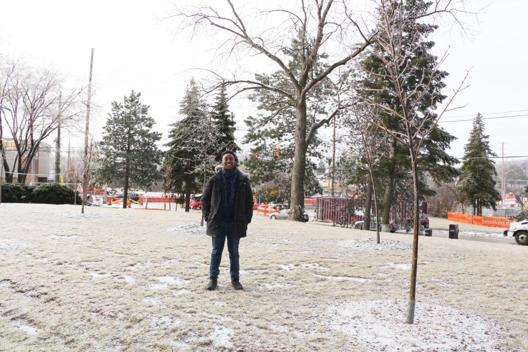 tenant standing in a park next to a tree and smiling