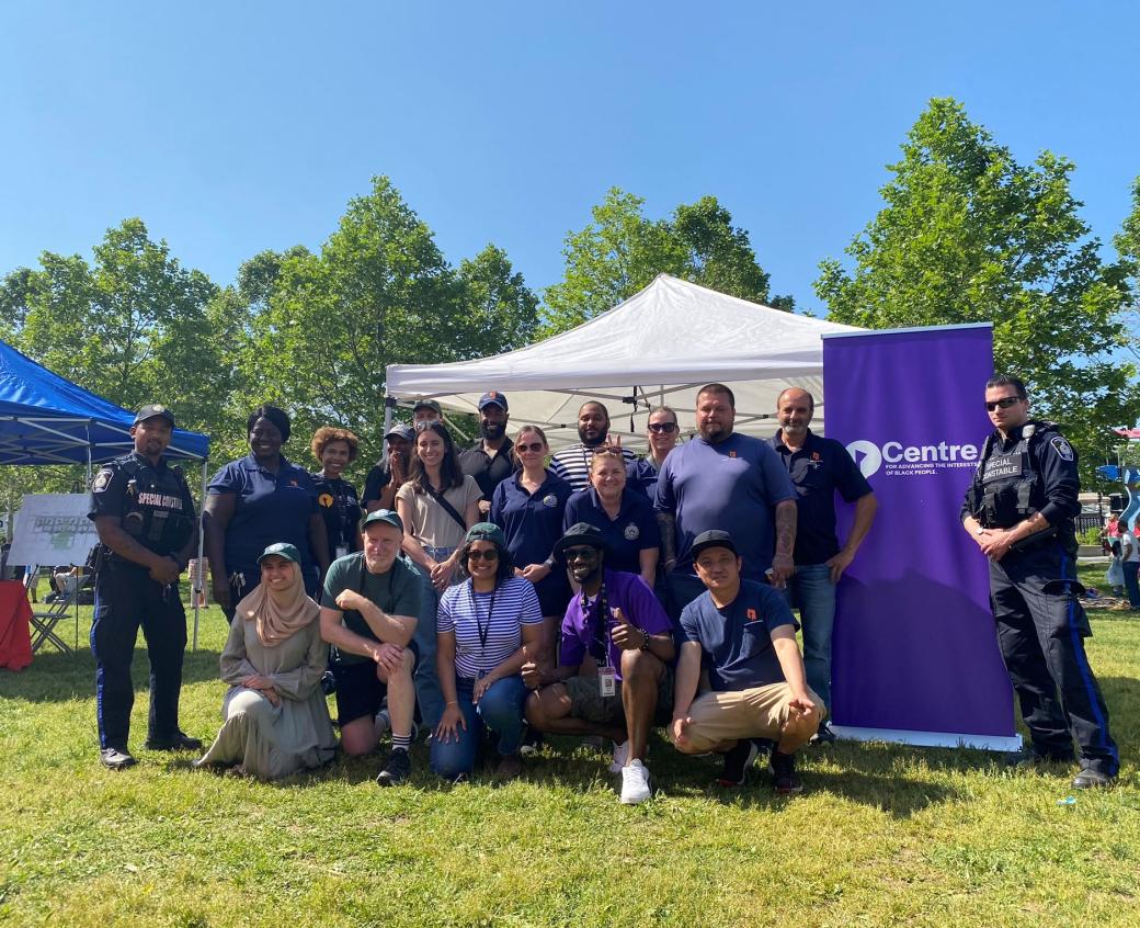 Group shot of people in a park in front of a banner for The Centre