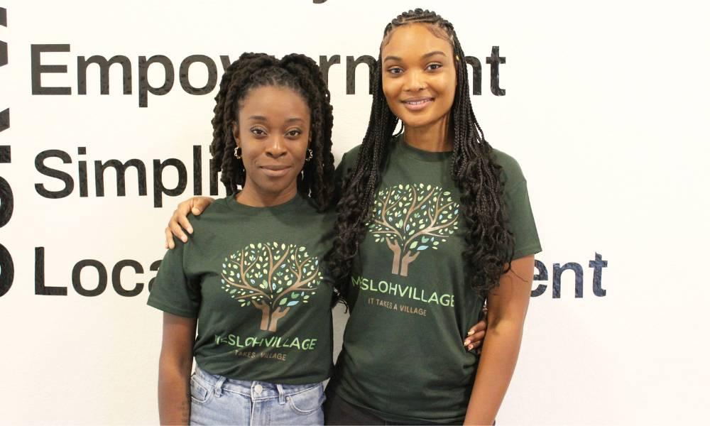 Sashalee Carty and Tamika Johnson standing inside in front of a large poster.