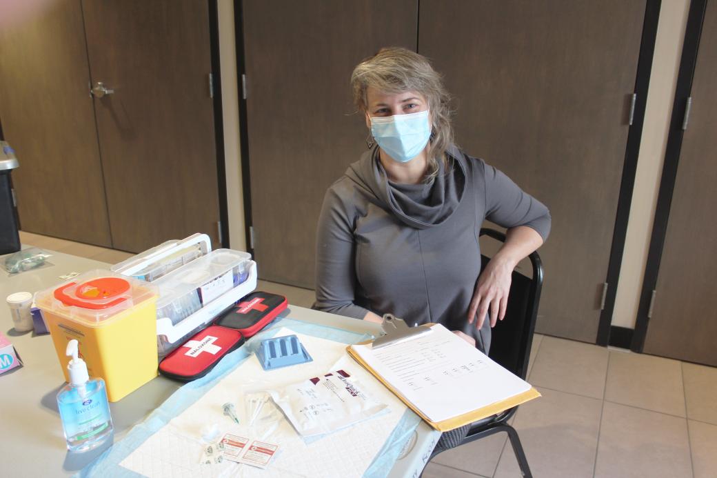 Woman wearing a protective mask sitting at a table with medical equipment