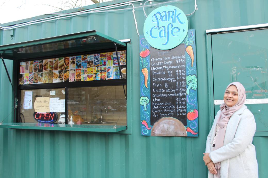 A woman stands in front the Park Cafe - a teal coloured snack bar