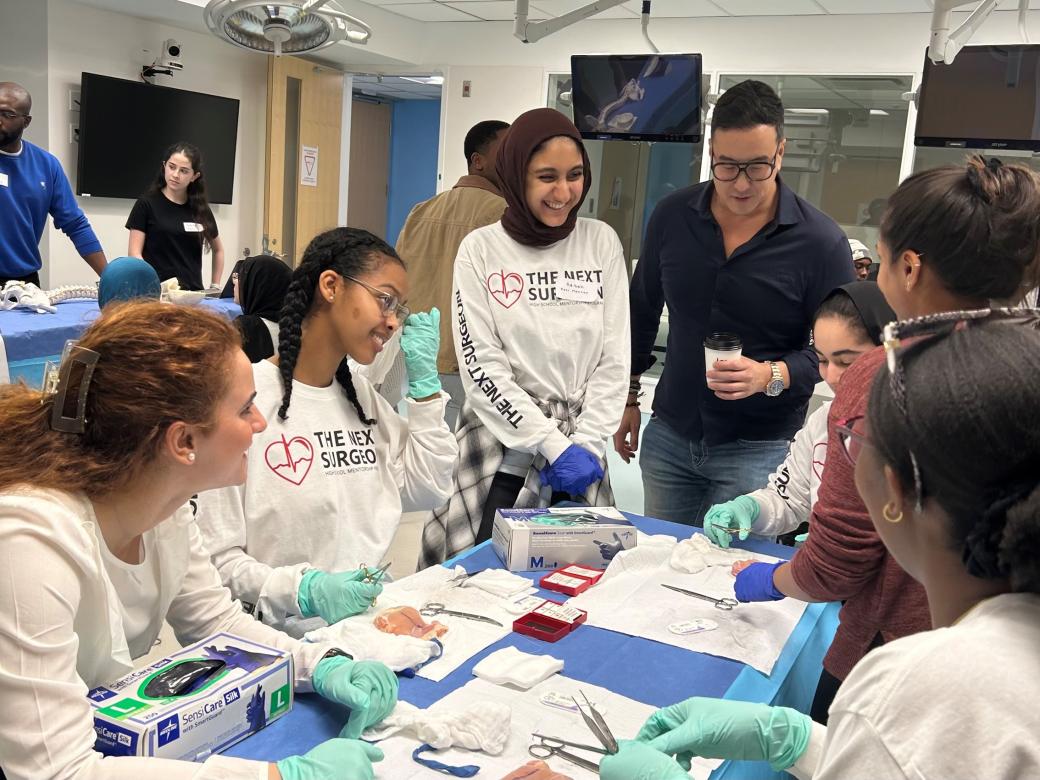 Program participants are shown standing around a table of surgical equipment