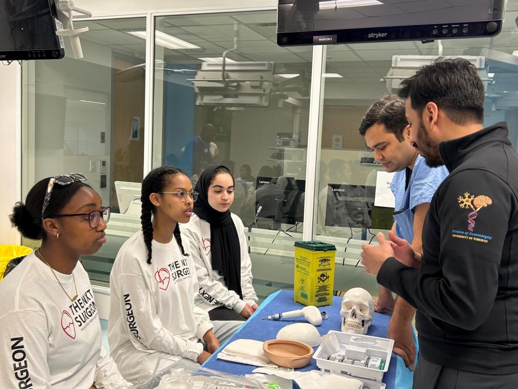 A group of youths listen to an instructor explain a medical procedure