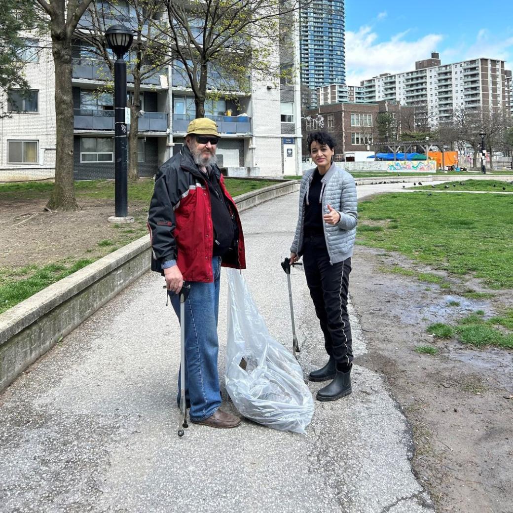 Two tenants are standing - one is holding a clear garbage bag and the other a garbage picker