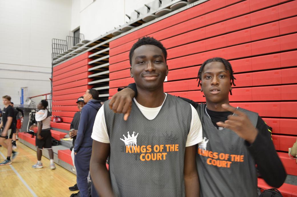 Two young men wearing Black “Kings of the Court” basketball jerseys.  