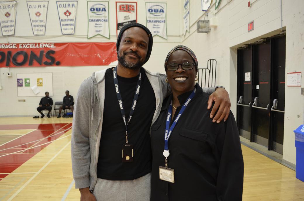 Two people standing in a gym posing for a camera. 