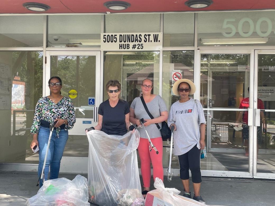 A group of TCHC’s tenant leaders and volunteers pose for a photograph at the entrance of a TCHC building with a sign, 5005 Dundas Street West. 